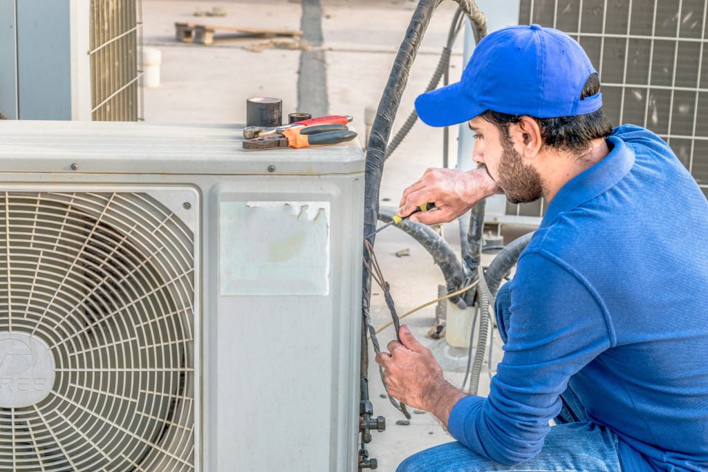 Technician repairing an outdoor AC unit, showcasing HVAC maintenance services for efficient cooling in homes.