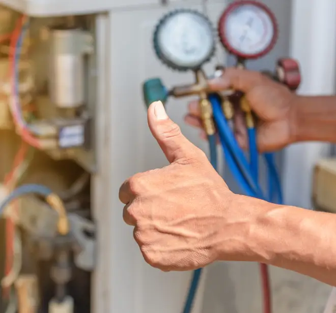 Technician giving a thumbs up while using HVAC pressure gauges, representing quality service and maintenance for commercial HVAC systems in Lake Orion.