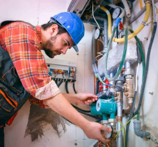 Technician in blue hard hat servicing heating system components, ensuring efficient operation and reliability for Lake Orion homes.