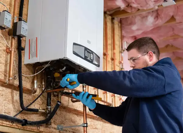Technician installing a heating system, wearing gloves and using tools, with a boiler and plumbing in a residential setting, emphasizing professional heating installation services.