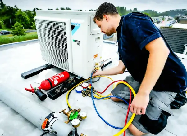 Technician servicing a Daikin air conditioning unit on a rooftop, using service tools and hoses for refrigerant levels and system checks.