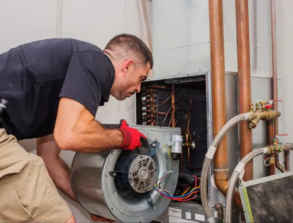 HVAC technician repairing air conditioning unit, focusing on motor installation, with copper pipes and electrical connections visible.