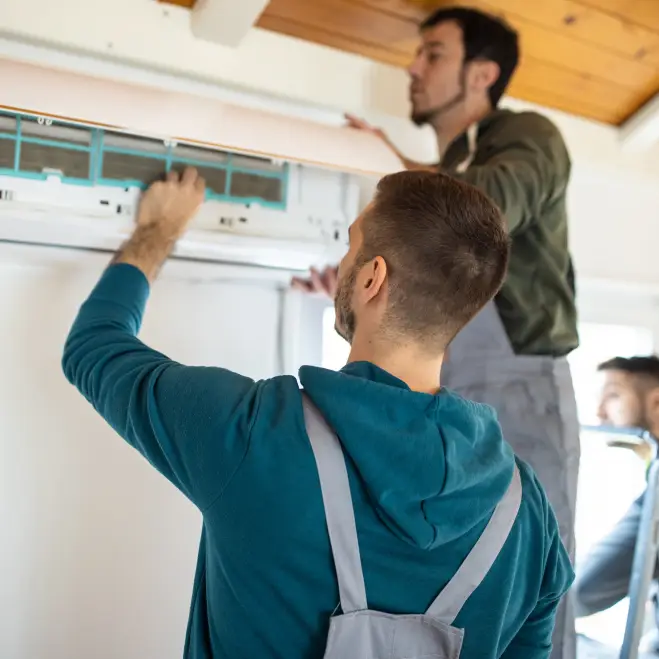 Technicians installing a ductless mini-split air conditioning system, ensuring efficient cooling for residential spaces.