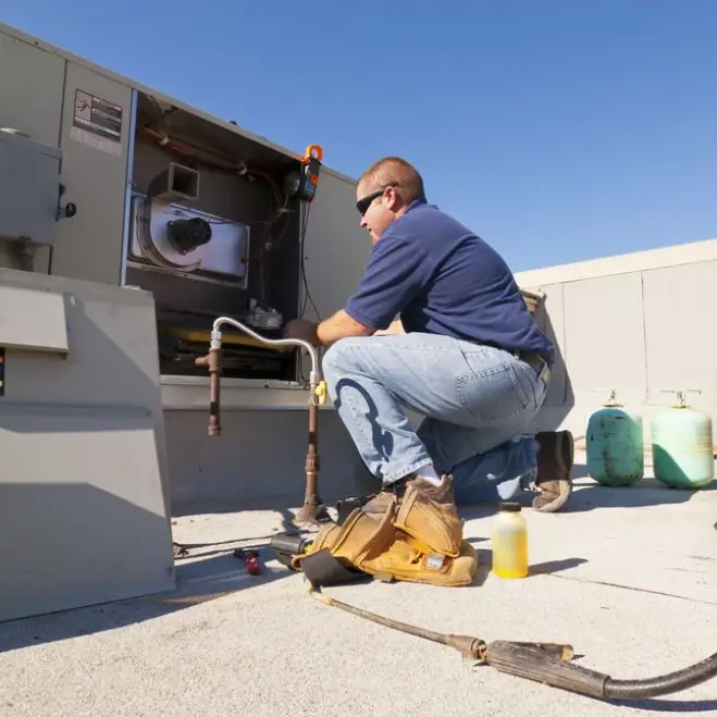 HVAC technician performing maintenance on rooftop cooling unit, showcasing expertise in HVAC services for Lake Orion residents.