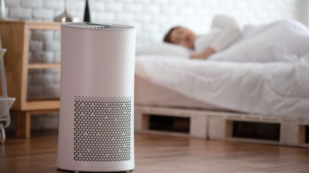 Indoor air purifier in a bedroom with a person sleeping, emphasizing indoor air quality solutions for healthier living.
