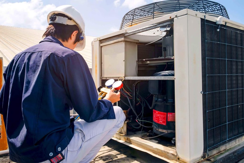 HVAC technician servicing an air conditioning unit, checking gauges and compressor, emphasizing maintenance and repair services in Bloomfield Hills.